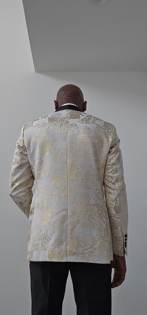 Man wearing a patterned Gold Jacket against a plain background