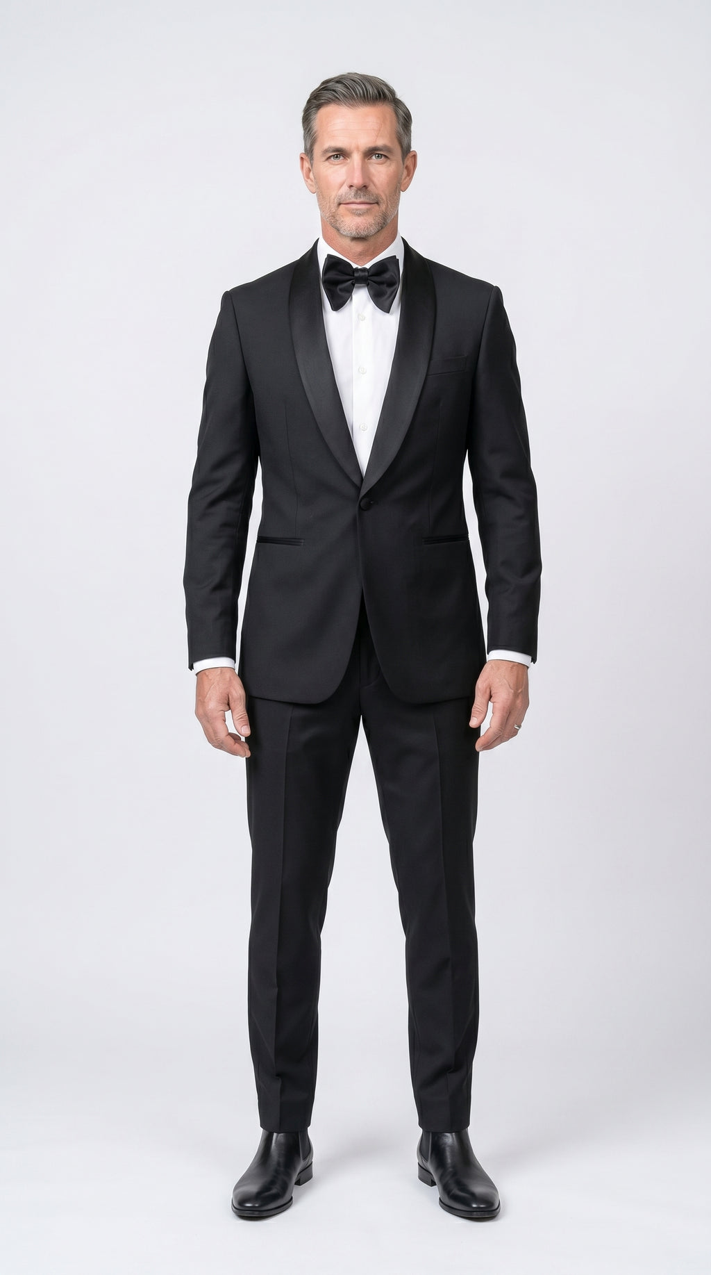 Man wearing a black tuxedo with a white shirt and black bow tie on a white background