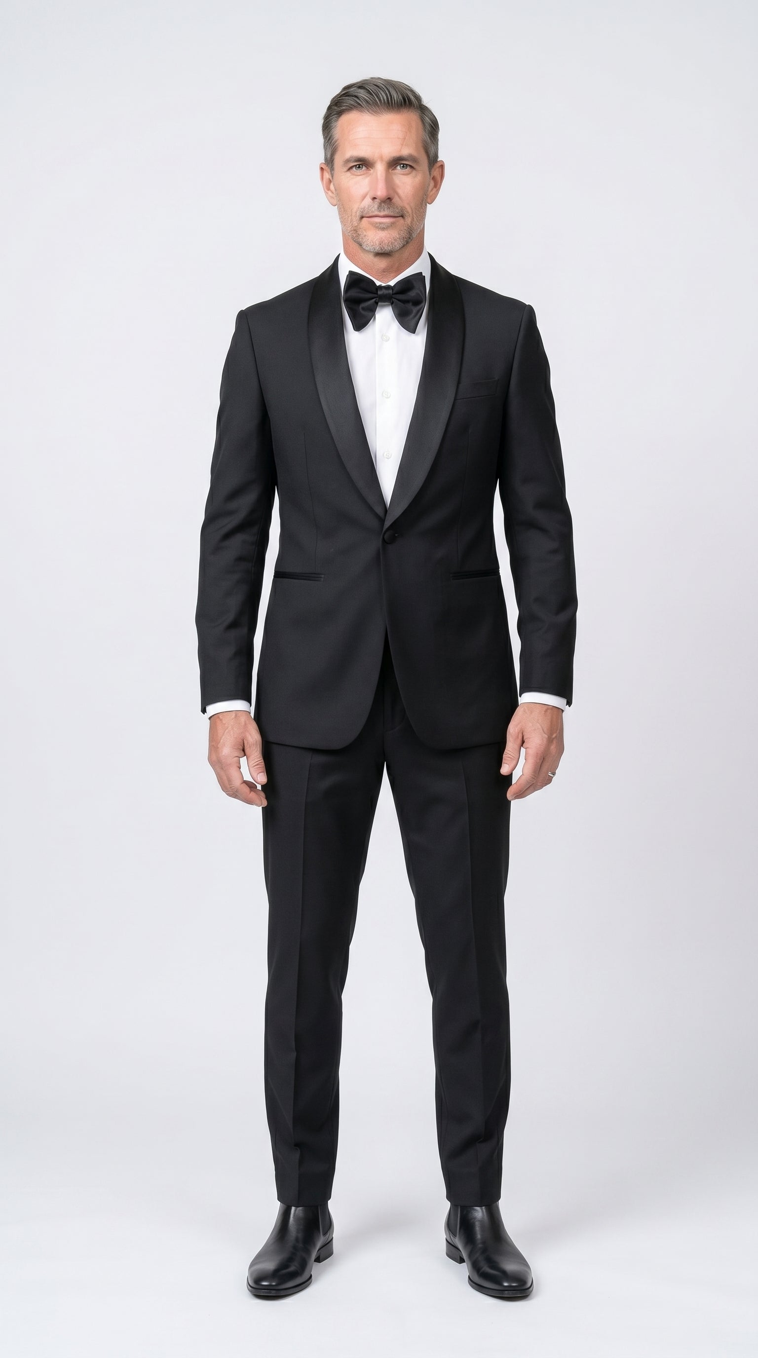 Man wearing a black tuxedo with a white shirt and black bow tie on a white background