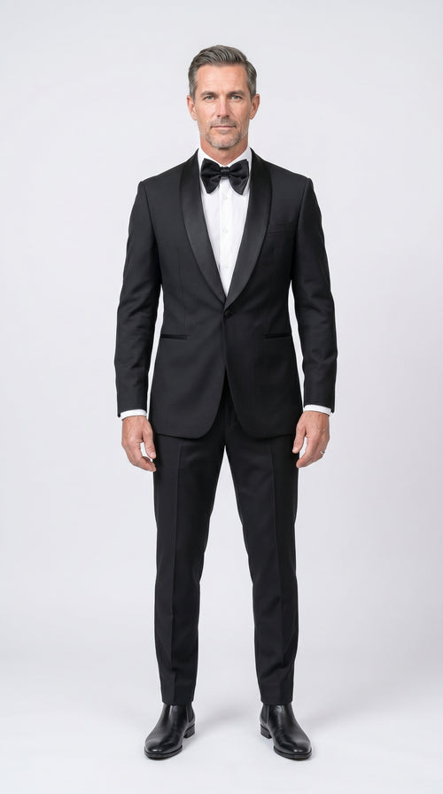 Man wearing a black tuxedo with a white shirt and black bow tie on a white background