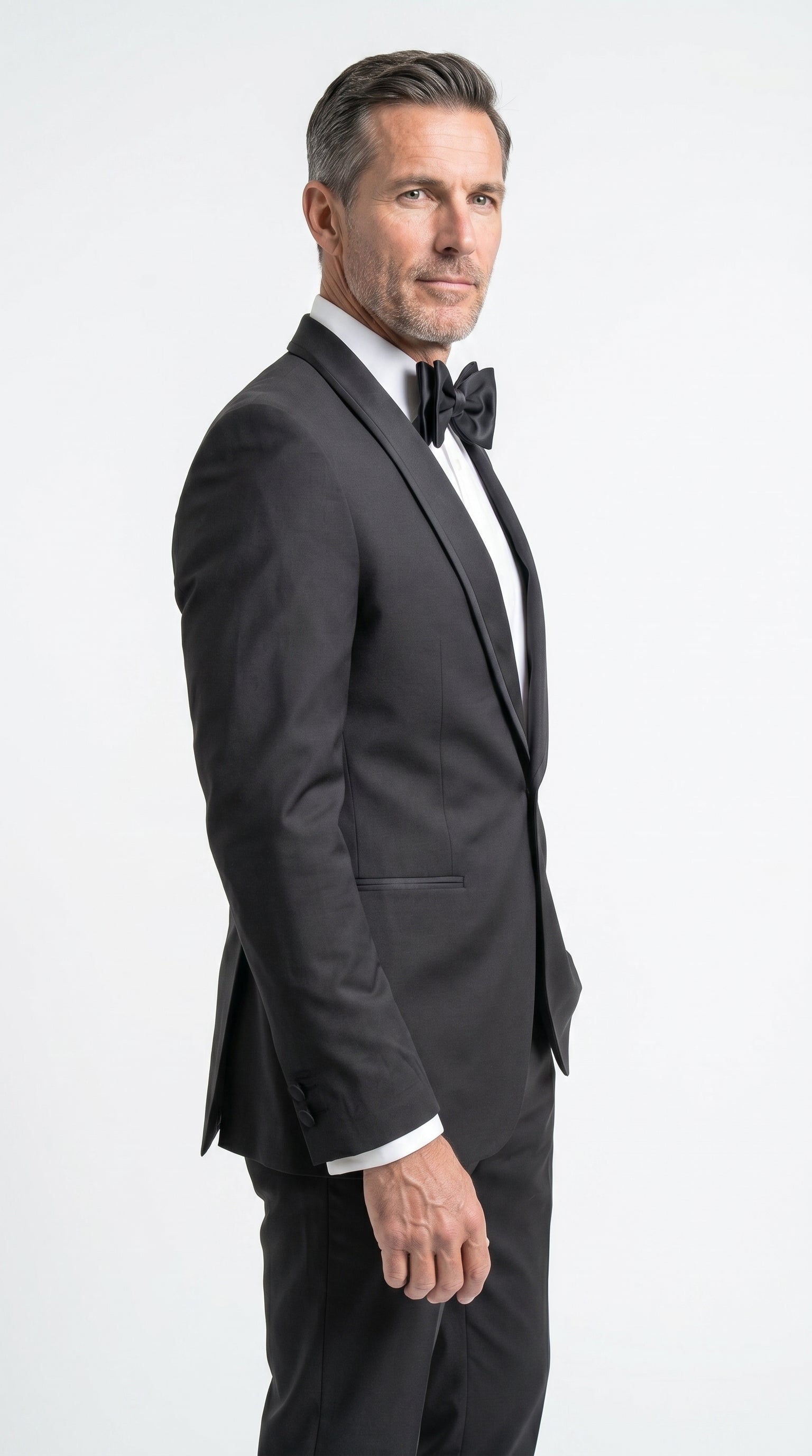 Man wearing a black tuxedo with a bow tie on a white background