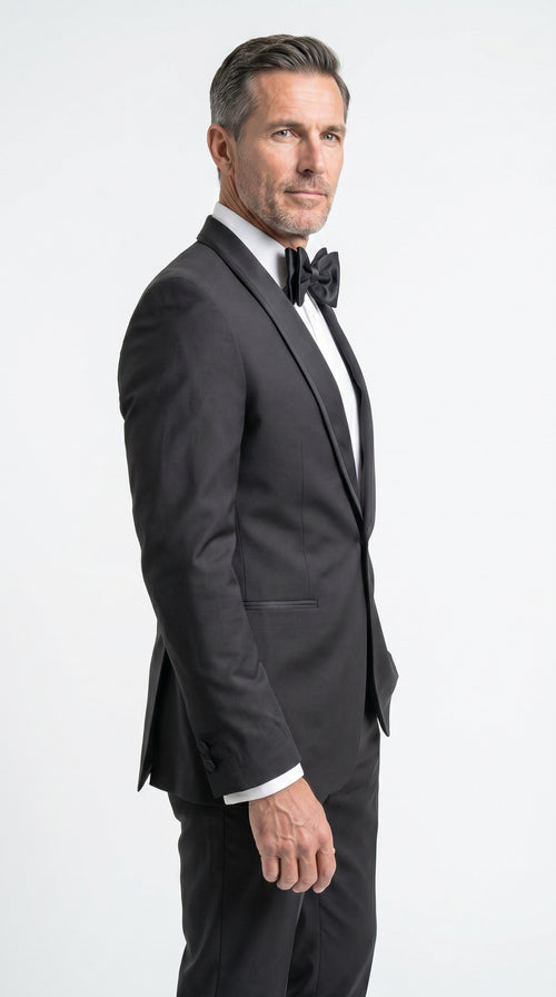 Man wearing a black tuxedo with a bow tie on a white background