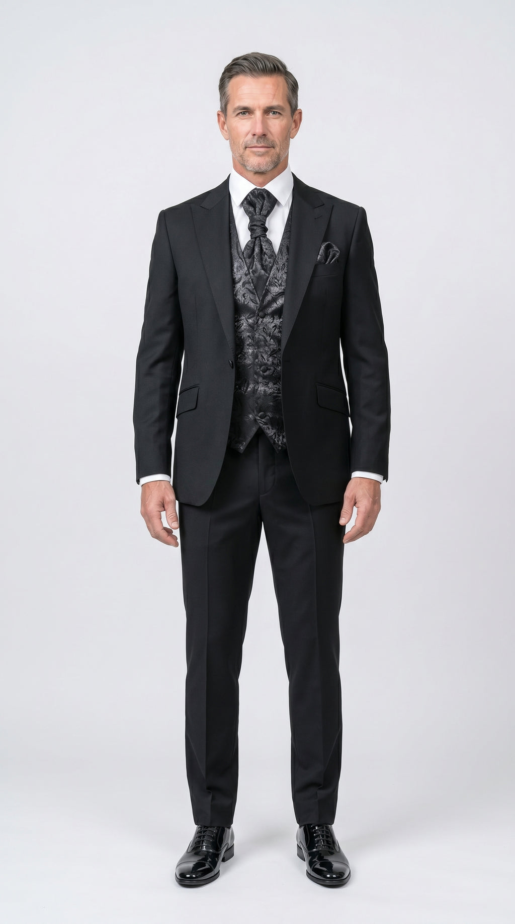 Man wearing a black suit with a patterned vest on a white background