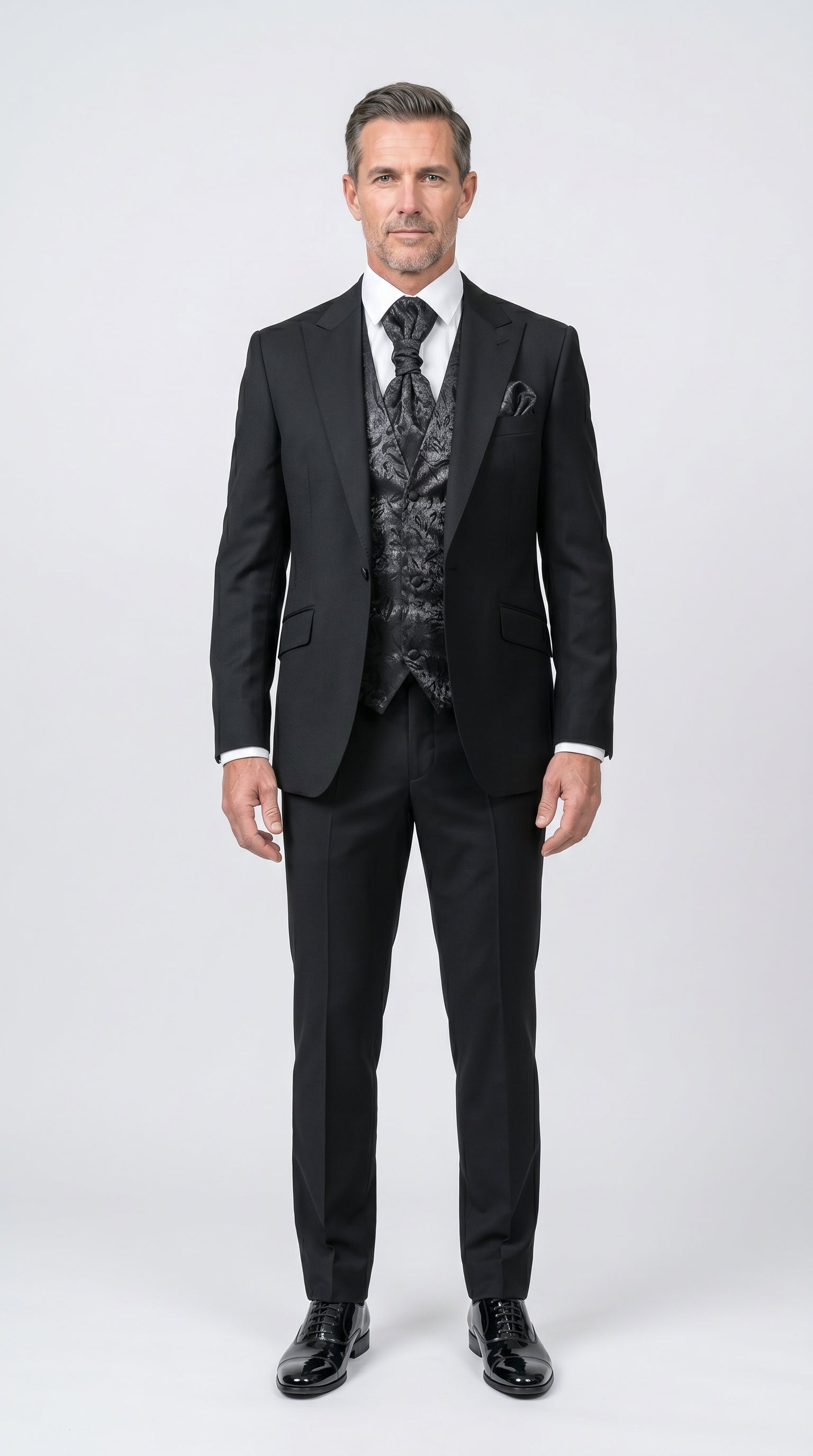 Man wearing a black suit with a patterned vest on a white background