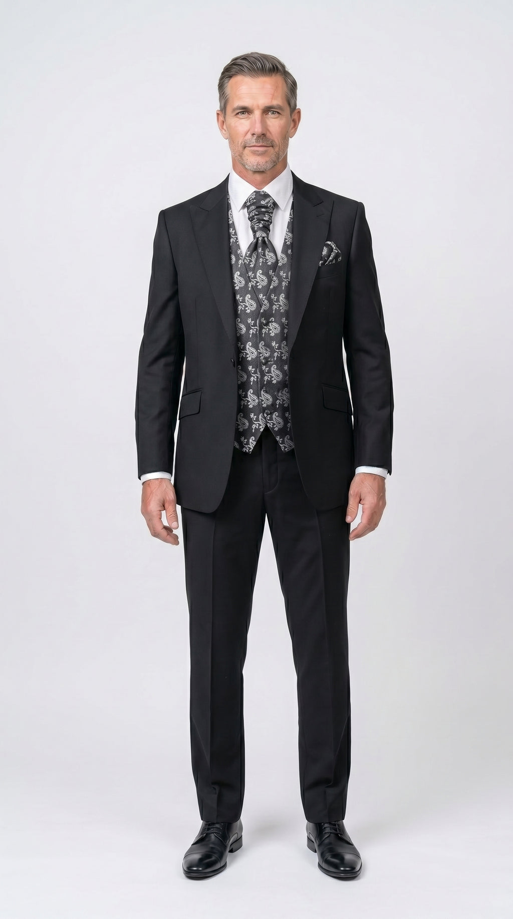 Man wearing a black suit with a patterned vest on a white background