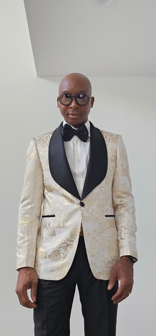 Man wearing a Gold tuxedo with black lapels and bow tie against a plain background