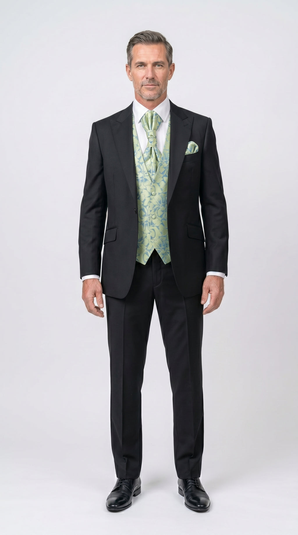 Man wearing a black suit with a green vest and tie on a white background