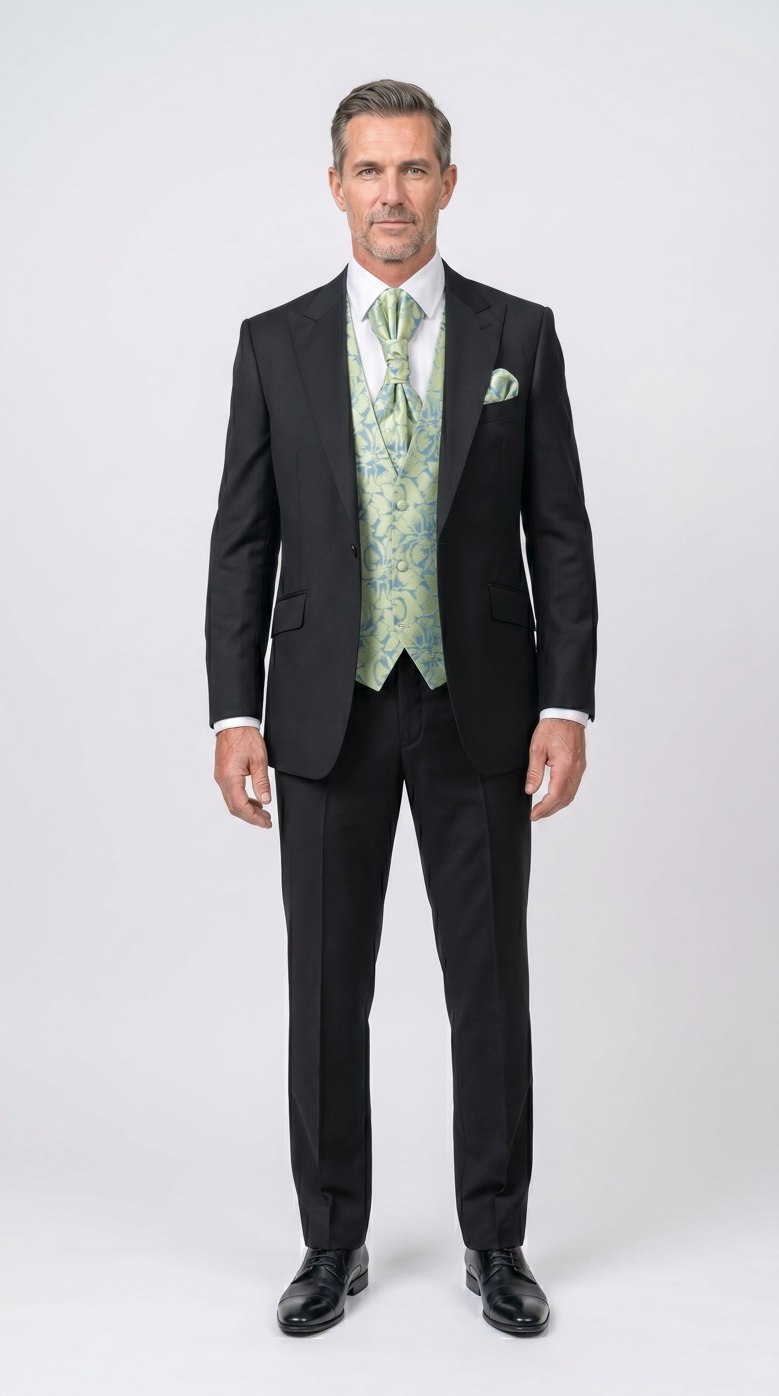 Man wearing a black suit with a green vest and tie on a white background