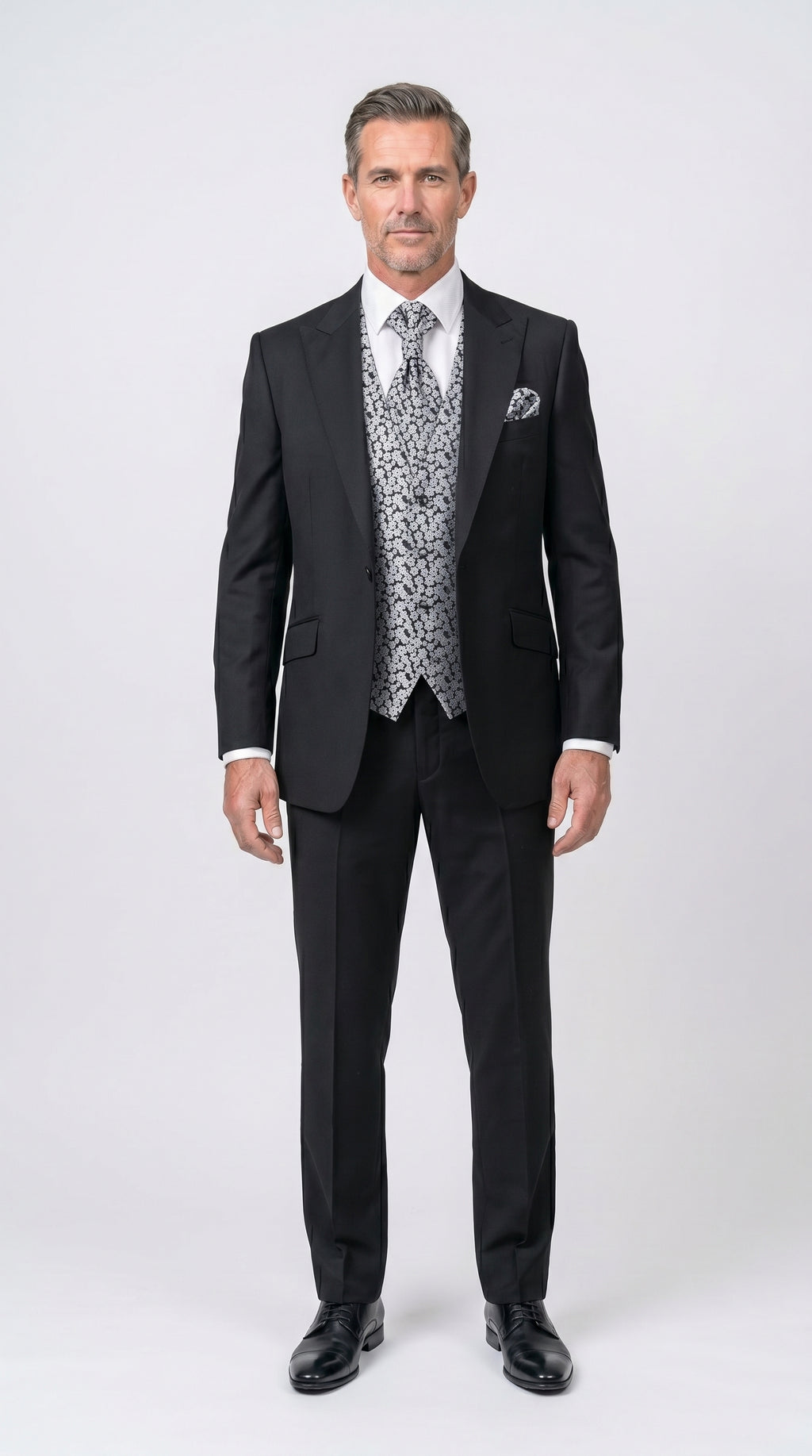 Man wearing a black suit with a patterned vest on a white background