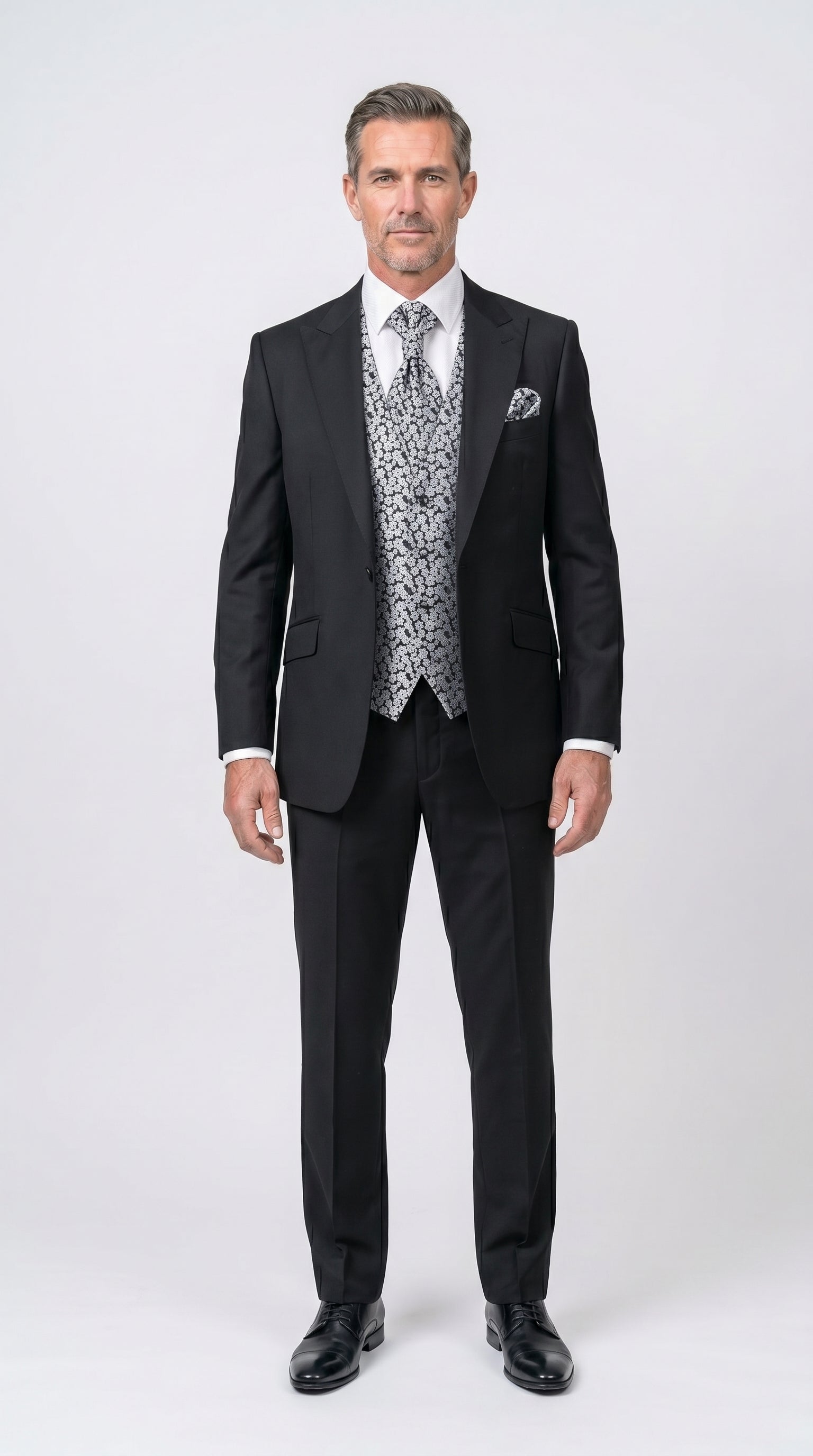 Man wearing a black suit with a patterned vest on a white background