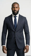 Man wearing a navy pinstripe suit with a white shirt and blue tie on a light gray background