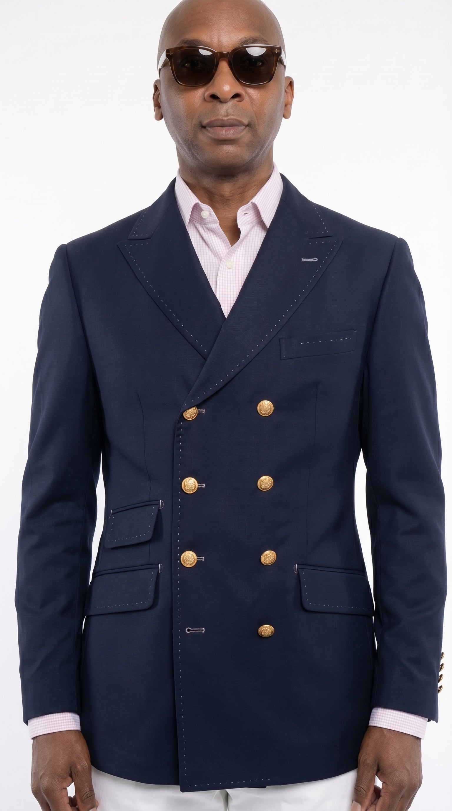 Man wearing a navy blue blazer with gold buttons on a white background