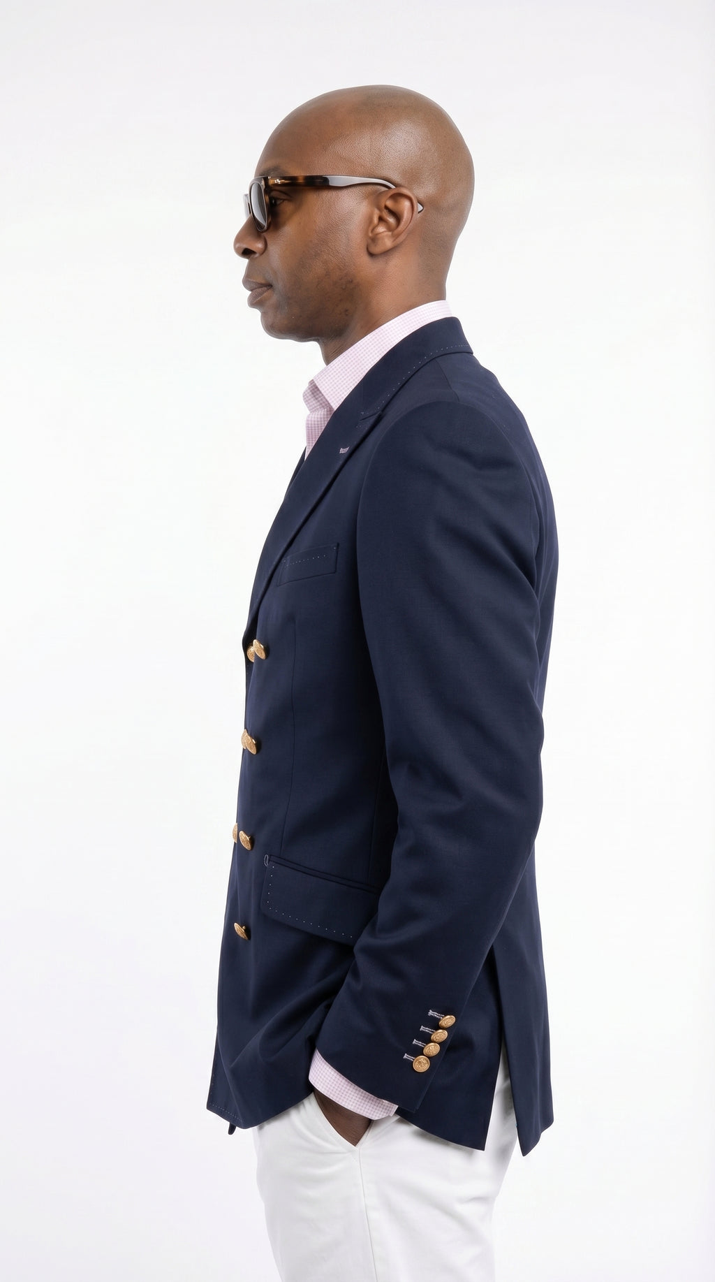 Man wearing a navy blazer with gold buttons on a white background