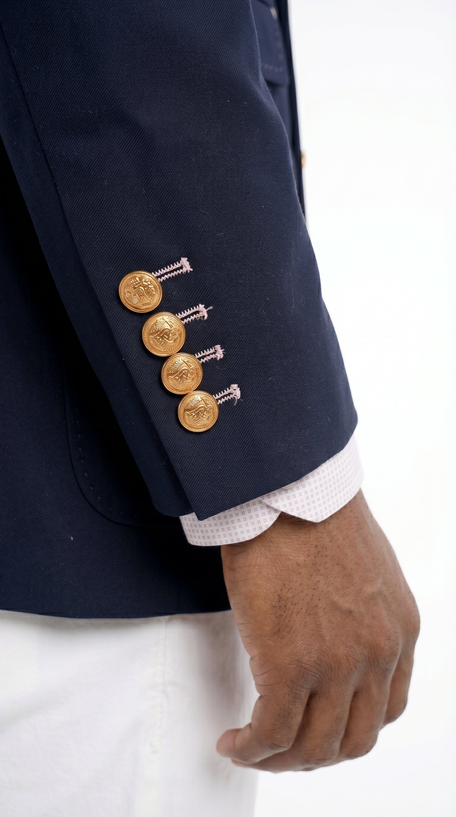 Navy blazer with gold buttons worn by a person on a white background