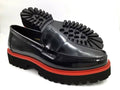 Black loafers with red soles on a white background