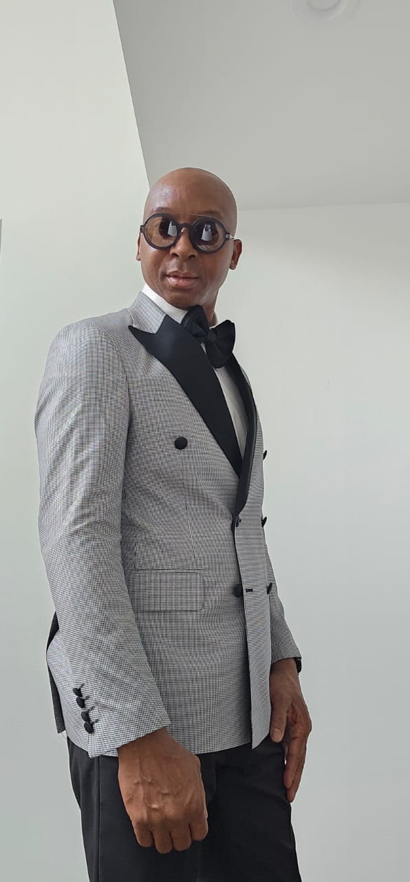 Man wearing a gray checkered suit with black lapels against a white background
