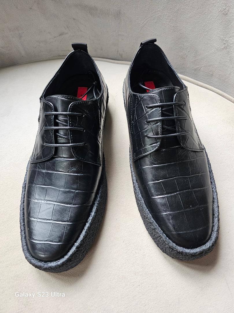 Pair of black leather shoes on a light gray surface