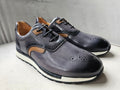 Pair of gray leather shoes with brown accents on a light surface.