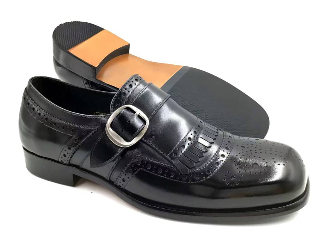 Black leather dress shoe with a buckle on a white background