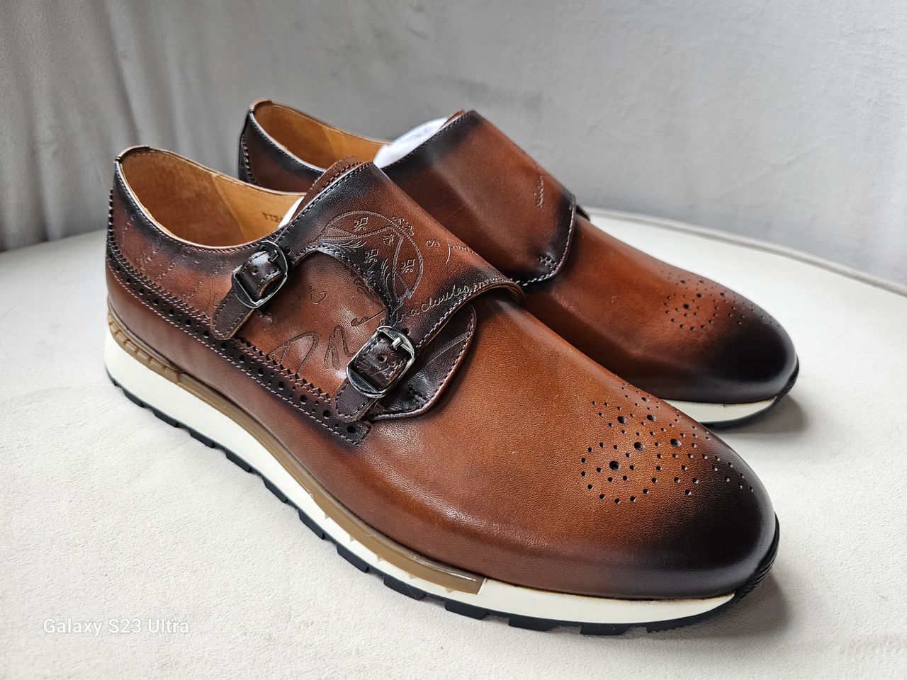 Pair of brown leather shoes with buckles on a light gray background
