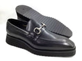 Black leather loafer with a decorative buckle on a white background