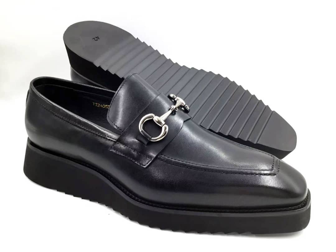 Black leather loafer with a decorative buckle on a white background