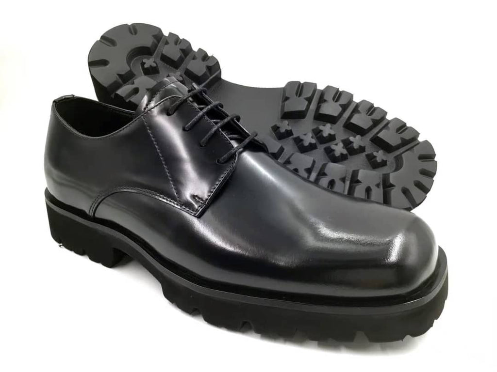Black leather shoe with a thick sole on a white background