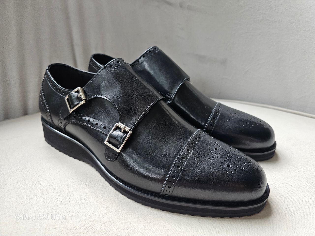 Pair of black leather shoes with buckles on a light background